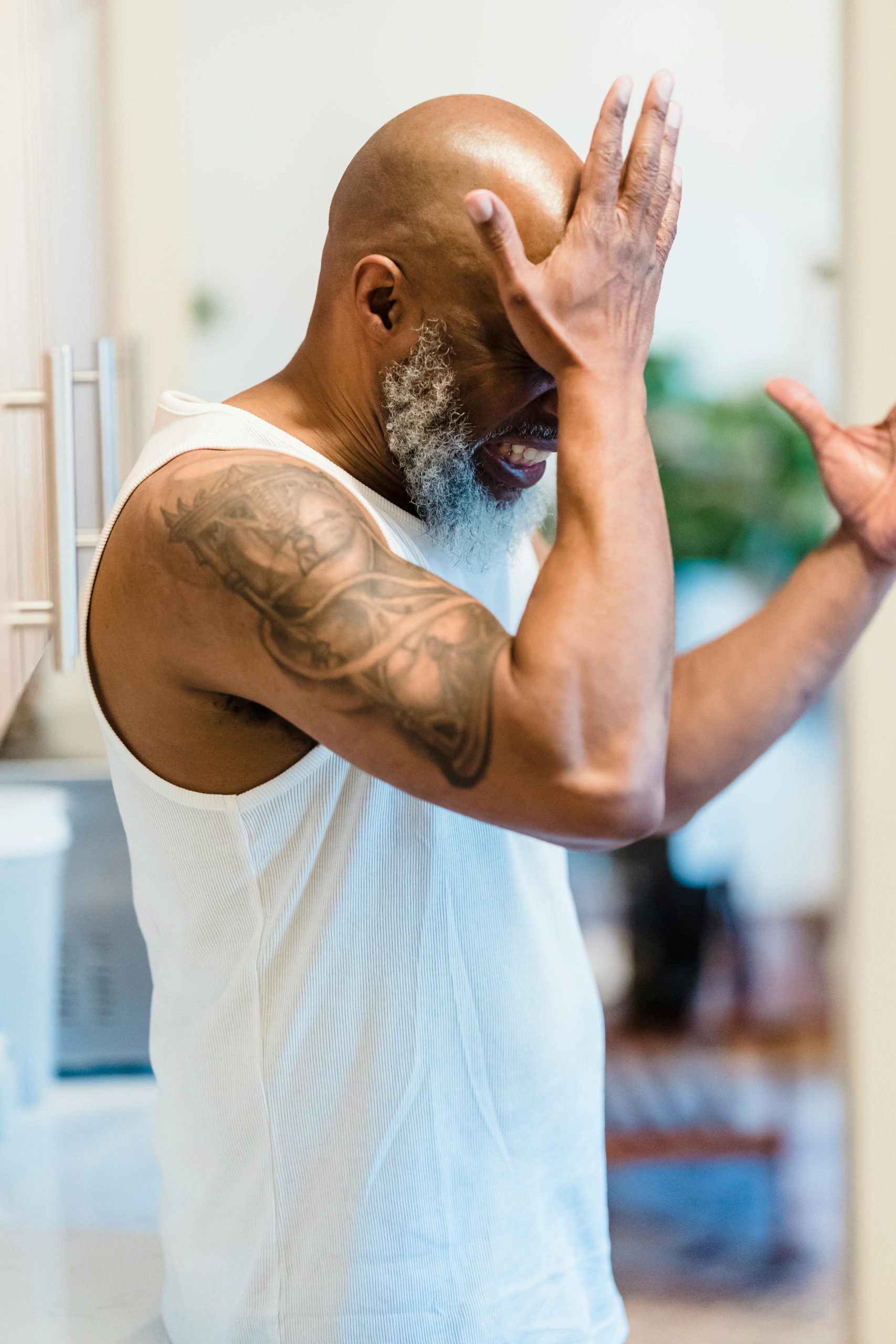 Un homme adulte avec un tatouage exprime du stress et des regrets dans un cadre intérieur.