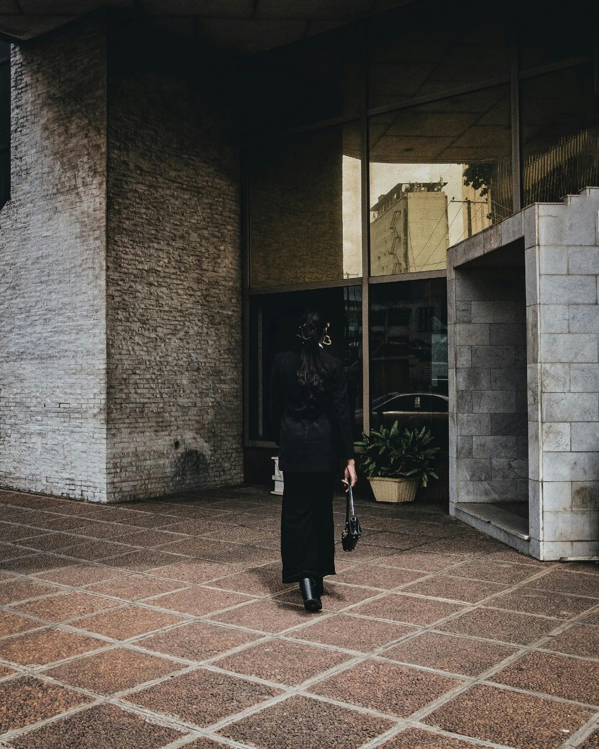 Sophistiquée en tenue noire marchant vers un bâtiment architectural moderne