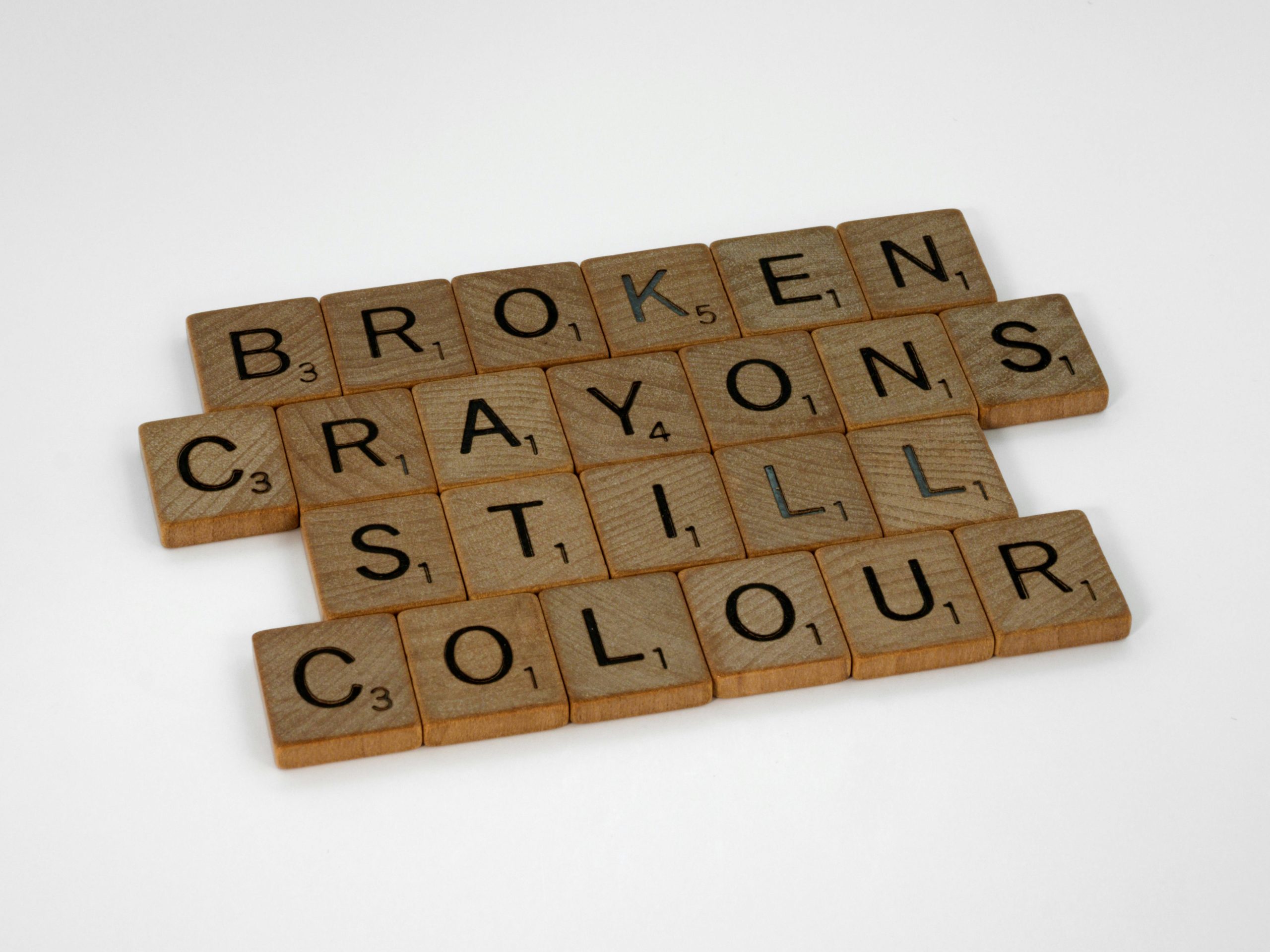 Scrabble tiles épelant « broken crayons still colour » sur un fond blanc